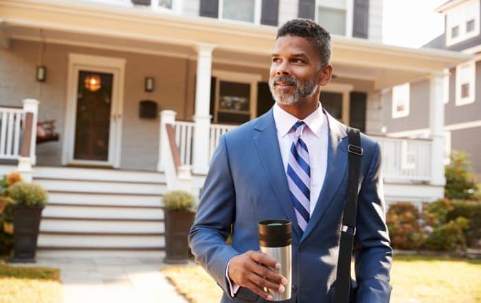 business man with coffee in front of house to represent insurance 101 for landlords_NREIG